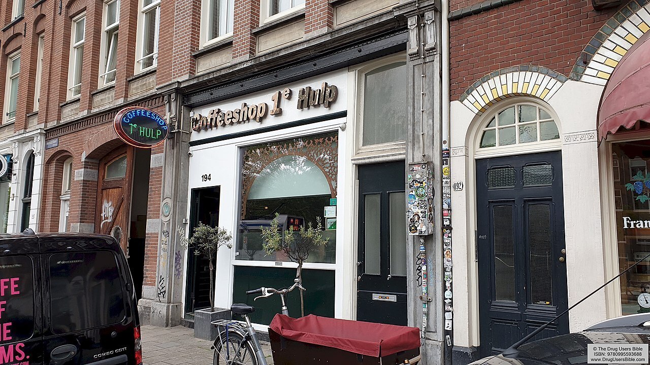 1e Hulp Amsterdam Coffeeshop store front view on a sunny day